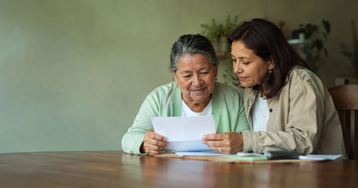 Madre mayor e hija revisando documentos para reclamar la pensión de sobrevivientes en Colombia